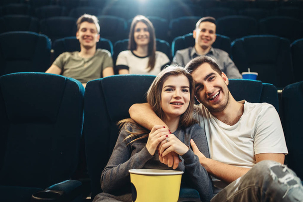 Young smiling man hugs his woman in cinema. Showtime, entertainment industry, movie watching - Photo, Image