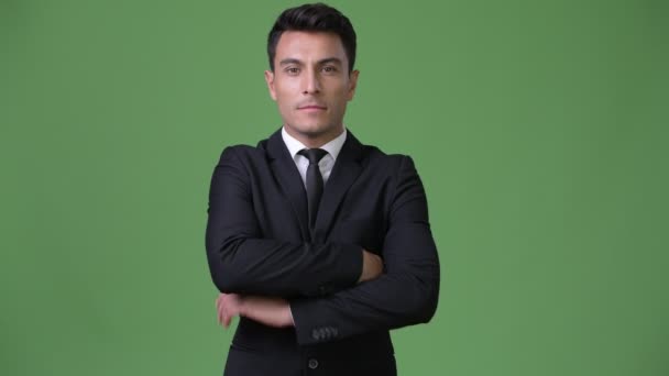 Young handsome Hispanic businessman against green background - Footage, Video
