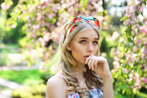 beauty and fashion concept. beauty girl with long blonde hair and stylish bow in garden with magnolia flower - Zdjęcie, obraz