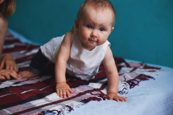 Adorable baby girl crawling at bed in living room. Childhood, parenthood, child development concept - Foto, afbeelding