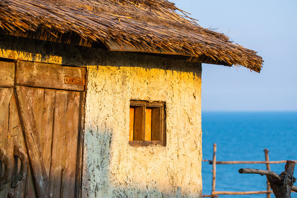 Oude traditionele witte croft huisje met rieten dak, met de zee in de baai. Concept van geïsoleerde schoonheid, instandhouding, bouwen met de natuur. - Foto, afbeelding