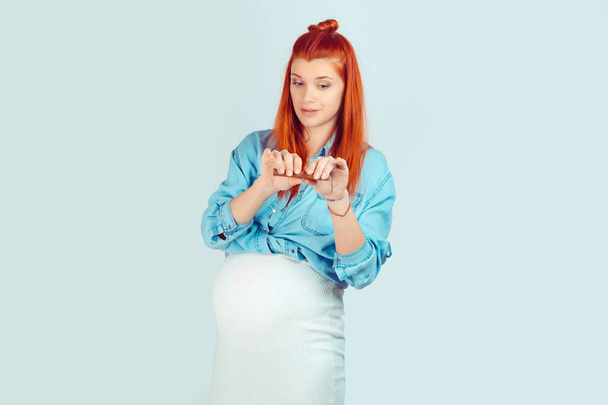 Confident young woman expecting baby standing isolated on light blue background and breaking cigar being against smoking. Mixed race model, latin hispanic irish woman - Фото, зображення