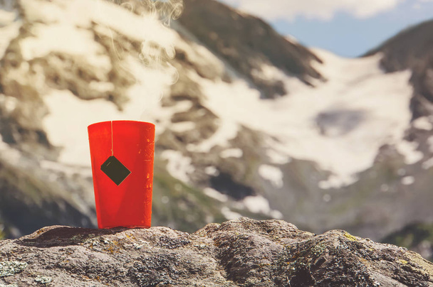 Una tazza di tè. Bevanda calda nella foresta. Picnic nel bosco. Turismo e viaggi. tazza con tè preparato in mezzo ai bellissimi laghi e alte montagne
 - Foto, immagini