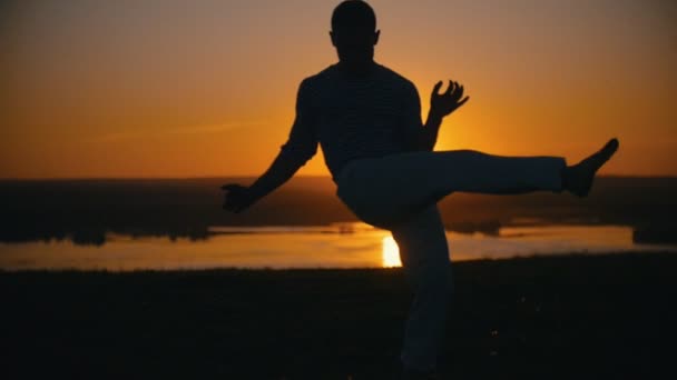 Un homme effectue des techniques de combat sur le fond du soleil couchant, au ralenti
 - Séquence, vidéo