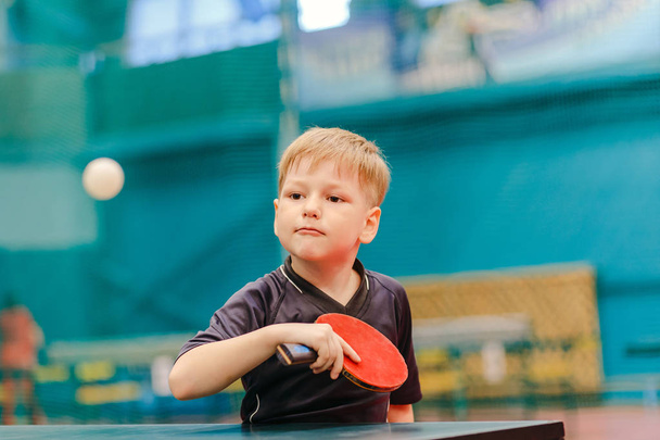 table tennis game, concentrated boy plays tennis ball in the tennis hall - Fotó, kép