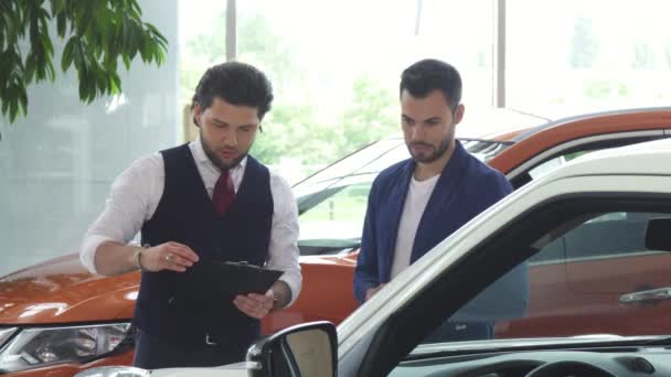 Profesionální auto prodejce prodávat nové auto mladému muži - Záběry, video
