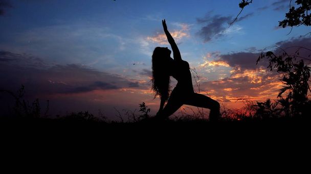 Femme faisant du yoga, silhouette féminine en fond de ciel en soirée
. - Photo, image