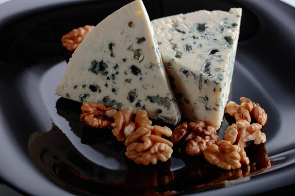 Compensées de fromage bleu à pâte molle aux noix sur une assiette noire
.  - Photo, image