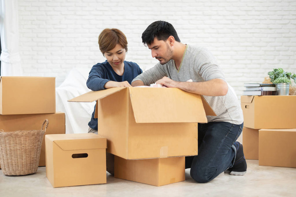 Happy Young Couple unpacking cardboard boxes at new home. Moving house. - Foto, Imagen