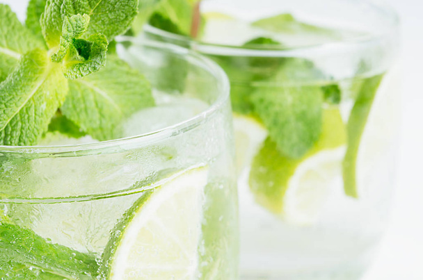 Twigs green mint in mojito with slices lime, ice cubes, straw, macro, texture, blur. - Foto, imagen