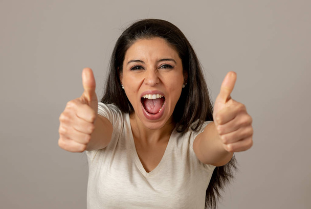 Young beautiful latin happy euphoric and excited woman celebrating winning the lottery. Thumbs up. Positive human facial expressions and emotions. People success, life perception, achievement - Photo, image
