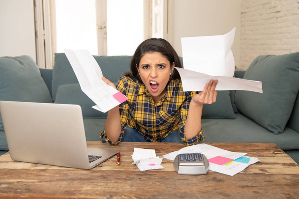 Young attractive woman worried at home banking and accounting home and credit card expenses with computer laptop doing paperwork in living cost stress and paying bills problem - Φωτογραφία, εικόνα