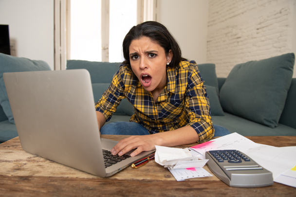 Young attractive woman worried at home banking and accounting home and credit card expenses with computer laptop doing paperwork in living cost stress and paying bills problem - Foto, Imagem