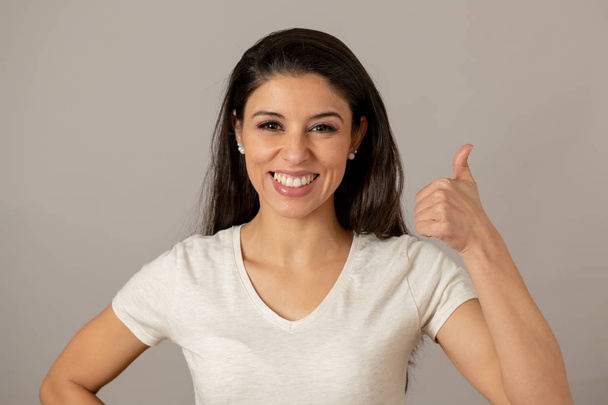 Close up beautiful young latin hispanic woman with a happy face. Beautiful smile and thumb up gesture. Positive human facial expressions - Foto, Bild