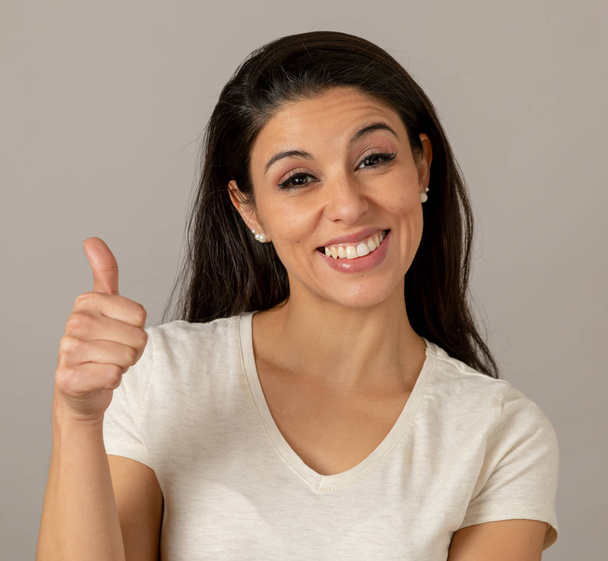 Close up beautiful young latin hispanic woman with a happy face. Beautiful smile and thumb up gesture. Positive human facial expressions - Фото, изображение