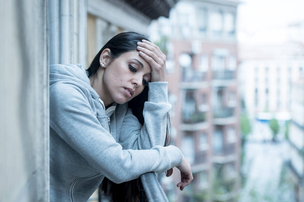Beautiful latin depressed lonely woman staring out feeling sad, pain, grief on a balcony at home. Crisis, depression and mental health concept - Photo, image