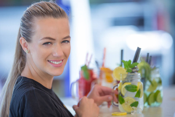 Attractive young woman with a beautiful smile while working in a bar preparing lemonades. - Foto, imagen