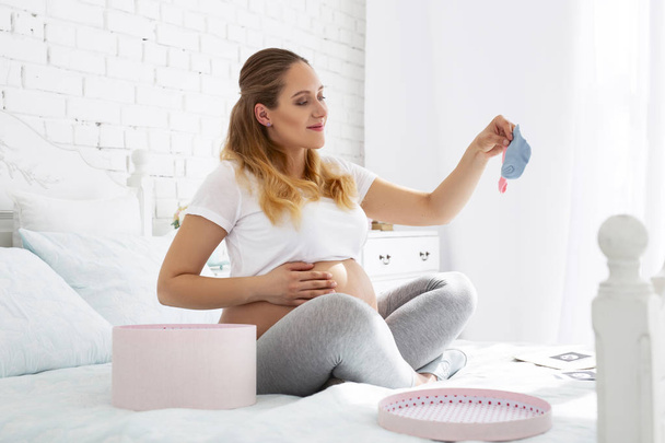 Charming pregnant woman studying socks - Foto, imagen