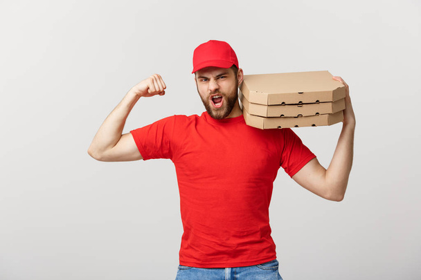 Delivery Concept - Portrait of Strong handsome delivery man flexing his muscle and holding pizza box packages. Isolated on Grey studio Background. Copy Space. - Фото, изображение
