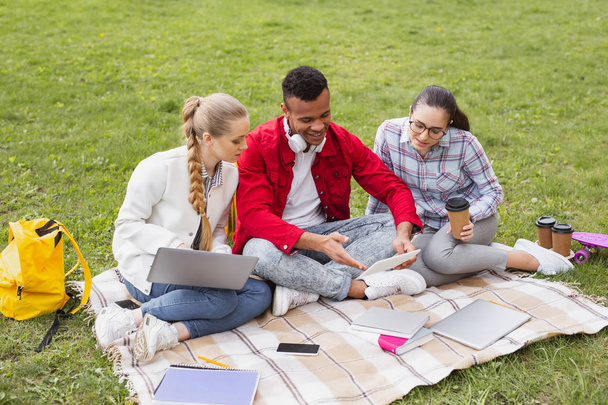 Три симпатичных студента сидят в парке рядом с университетом
 - Фото, изображение