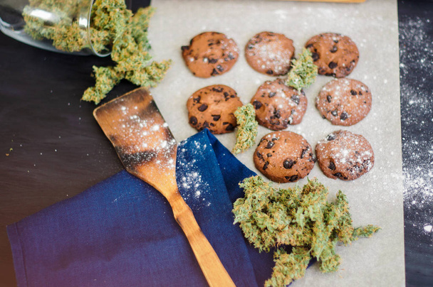 Concepto de cocinar con hierba de cannabis Galletas con cannabis y cogollos de marihuana sobre la mesa
. - Foto, Imagen