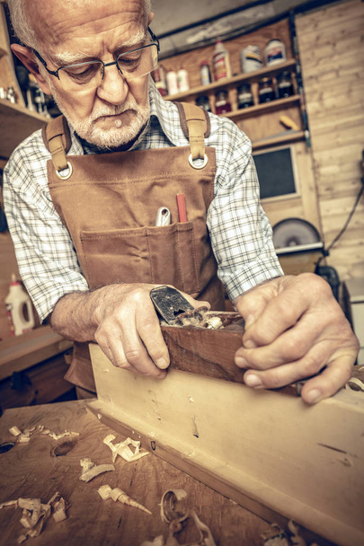 professional carpenter works with the planer on a beam - Fotó, kép