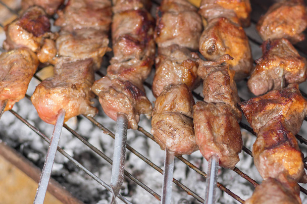 Trozos de sabrosa carne de cerdo en pinchos de cocina al aire libre en carbones ardientes
 - Foto, imagen