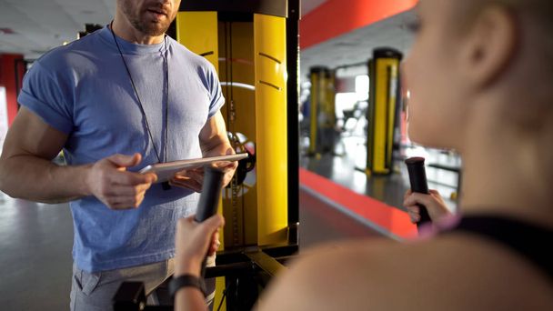 Fitness trainer talking to young woman gym, discussing training program, advice - Fotoğraf, Görsel