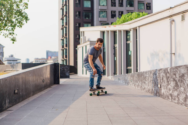 Young handsom man with beard riding a longboard on the street. - Foto, Bild