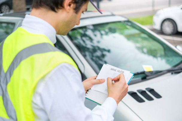 Ένας αρχιφύλακας στάθμευσης γράφοντας ένα εισιτήριο για μια παραβίαση στάθμευσης - Φωτογραφία, εικόνα