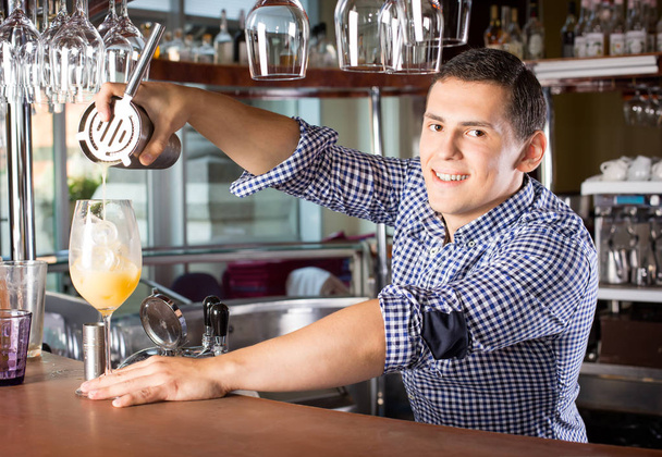 Sorridente barista bello versando un drink nel bicchiere fuori
 - Foto, immagini