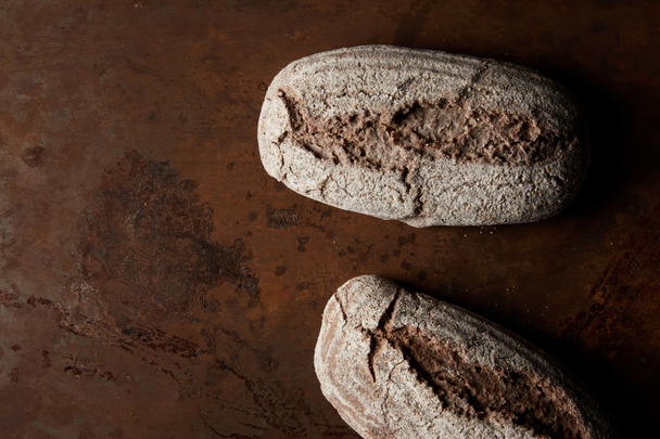 elevated view of bread on rusty brown metal tabletop  - Fotoğraf, Görsel
