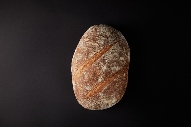 υπερυψωμένη θέαση του ψωμιού στο σκοτεινό ρουστίκ επιτραπέζια - Φωτογραφία, εικόνα