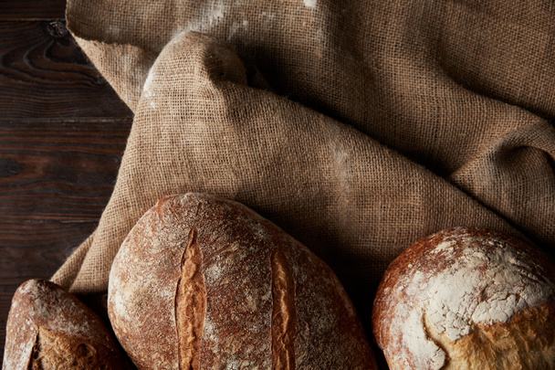 pohled shora různých druhů chleba a žíně na dřevěný stůl  - Fotografie, Obrázek