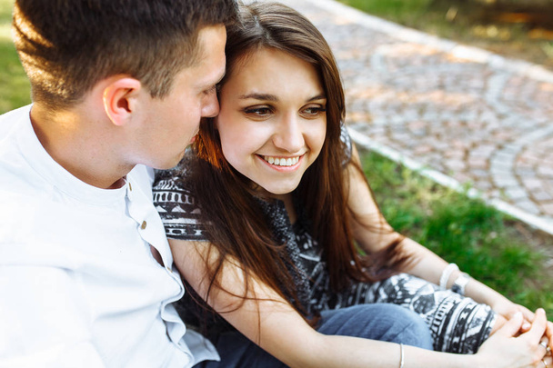 joven, feliz, pareja amorosa, sentados juntos en la hierba en el Parque, y disfrutando el uno del otro, la publicidad
, - Foto, imagen