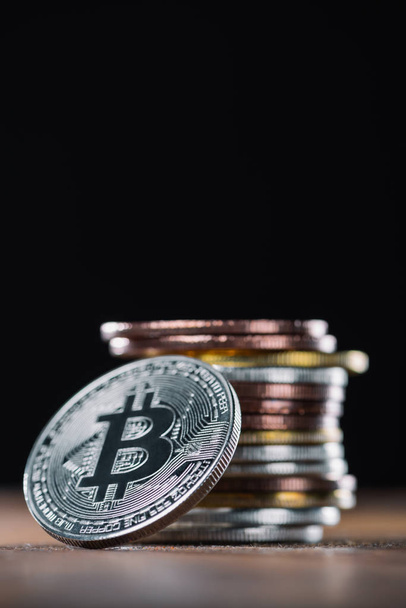 close up vista de bitcoin inclinando-se na pilha de vários bitcoins no fundo preto
 - Foto, Imagem