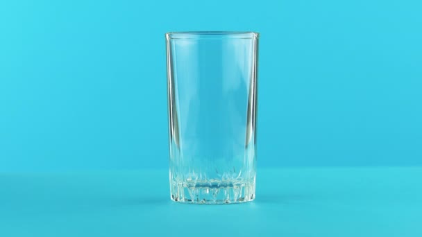 4K крупним планом знімок молока холодного напою, який бідний на різьбовому скляному синьому фоні в студії
 - Кадри, відео