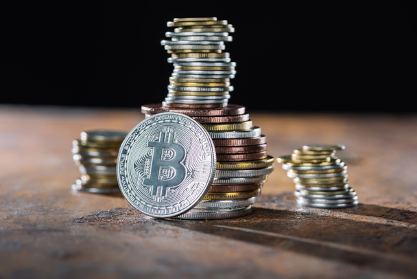 selective focus of silver bitcoin and piles of bitcoins behind - 写真・画像