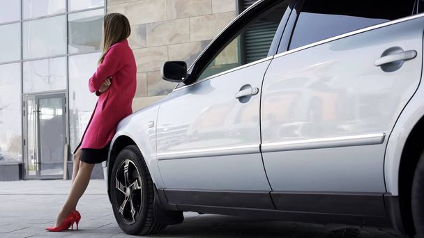 Pretty sad female standing near automobile and waiting for boyfriend, loneliness - Foto, Imagen