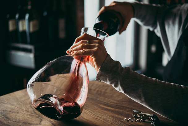 Pouring red wine into a decanter for breathing. - Valokuva, kuva