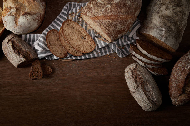 top view of various types of bread and sackcloth on wooden table - Foto, Imagen