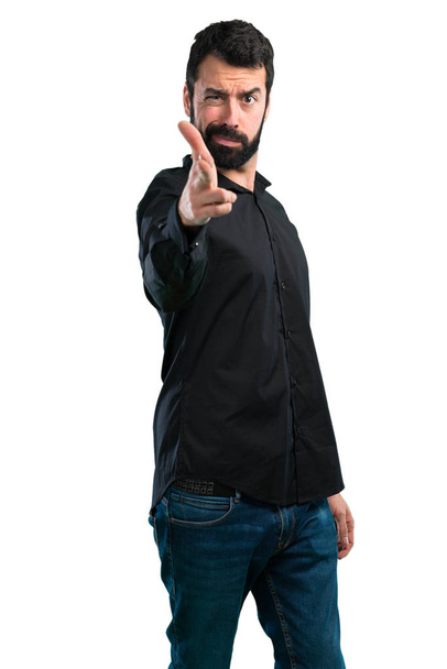 Красавчик с бородой делает пушечный жест на белом фоне
 - Фото, изображение