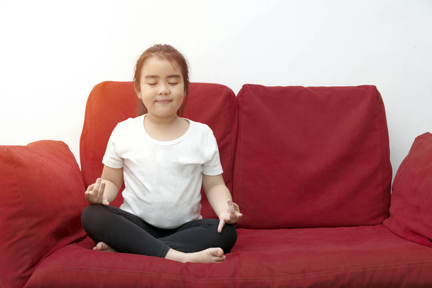 Meditate yoga hands of Asia Girl doing meditation in silhouette sunset and lens flair effect.Healthcare, lifestyle concept. National Yoga Awareness Month,Sitting on red sofa. - Zdjęcie, obraz
