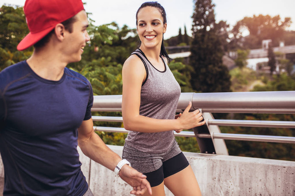 Happy couple running across the bridge. Healthy lifestyle. - Photo, Image