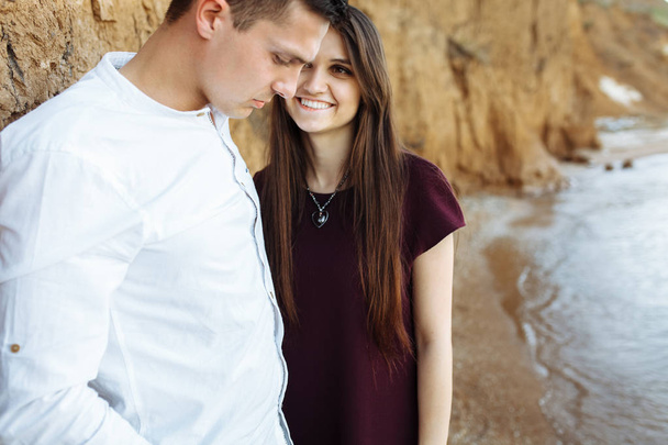 junges, glückliches, liebevolles Paar, in der Nähe der Sandmauer, am Meer posierend - Foto, Bild