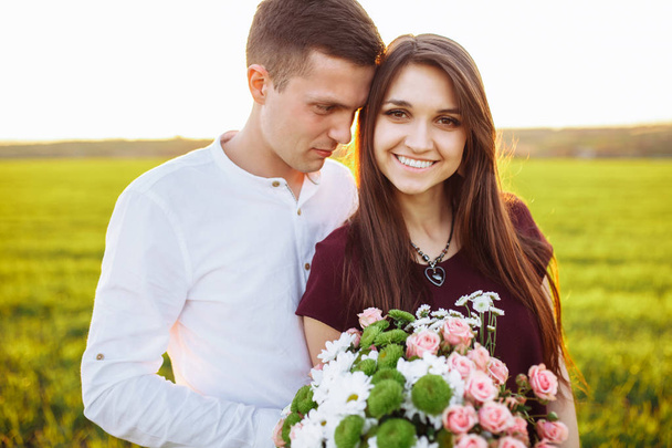 молода щаслива пара закохана, дівчина тримає квіти, щаслива і насолоджується компанією один одного, реклама
, - Фото, зображення