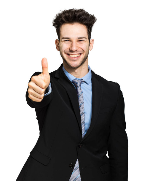 Smiling young businessman showing thumbs up - Foto, afbeelding