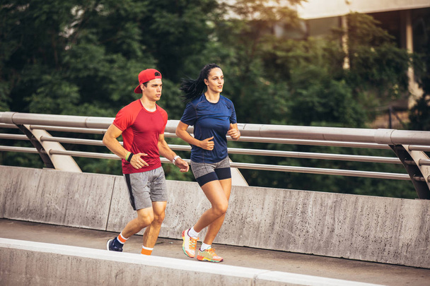 Happy couple running across the bridge. Healthy lifestyle. - Foto, Imagem