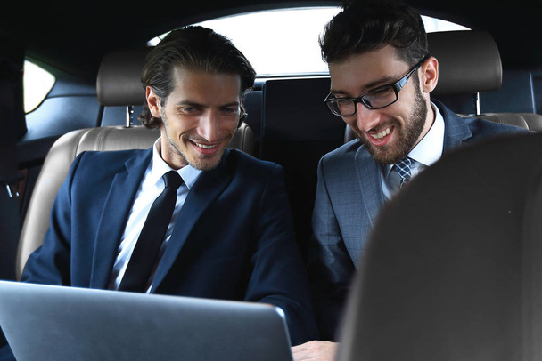 two businessman talking while sitting in the car - Foto, imagen