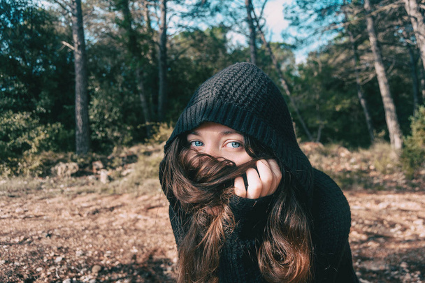 a girl with long hair and blue eyes in the mountain covering her face with her hair - Photo, Image